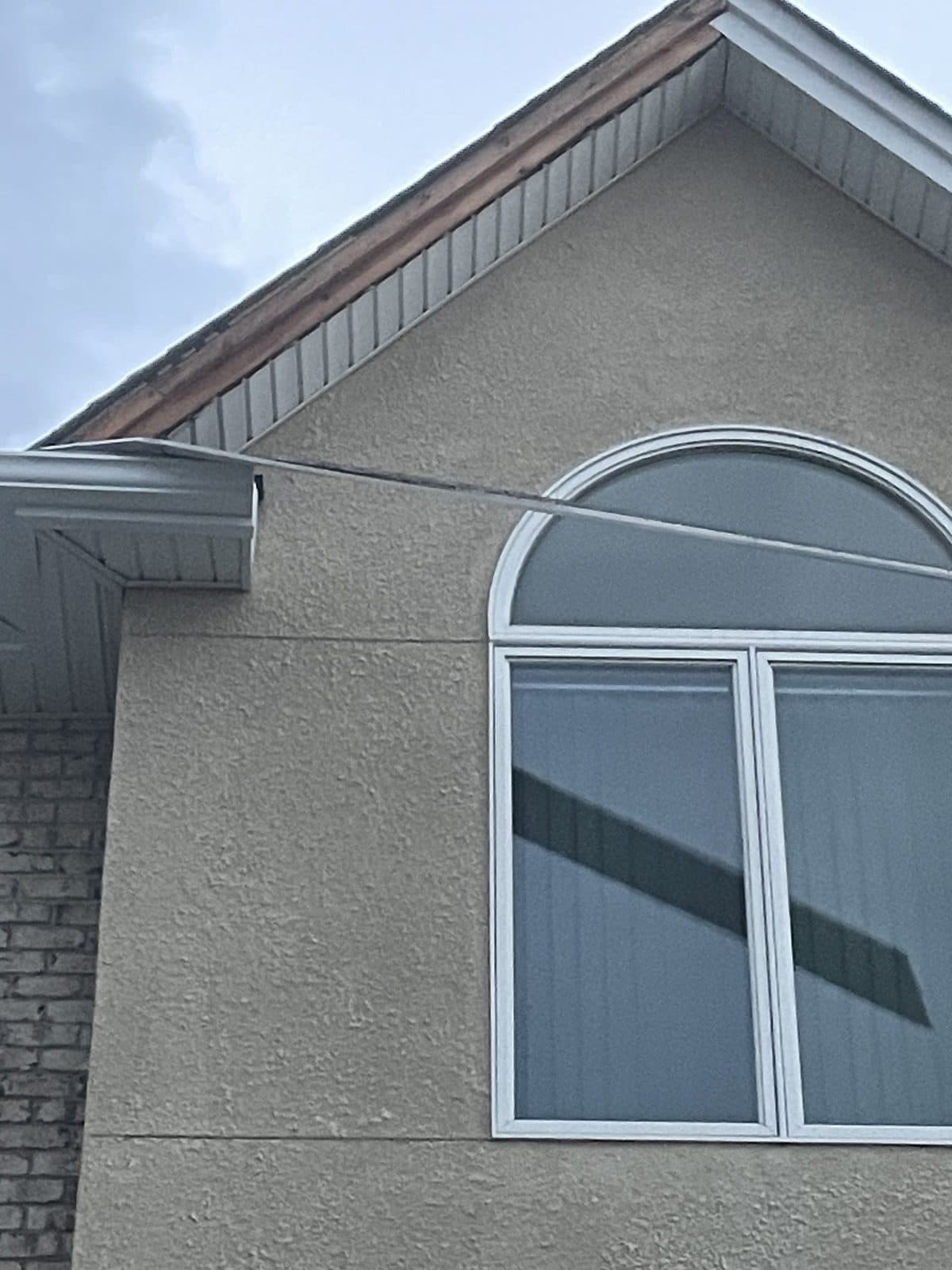 White half-round arched Palladian window over two rectangular units in the stucco gable of a Fair Lawn, NJ home, installed by Precision Windows & Glass